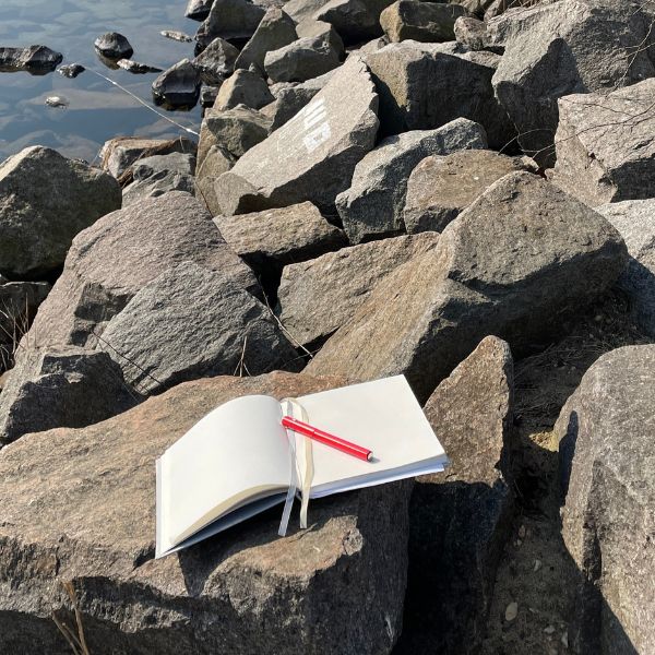 Große Steine am See und darauf ein Notizbuch