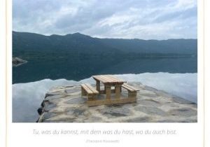 Bank am See mit Bergen in einer Spiegelung